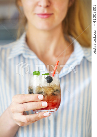 Woman holding blueberry cocktail with ice Woman holding blueberry cocktail with ice 41002803