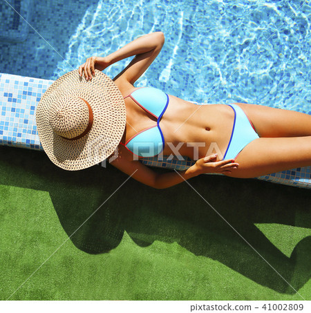 Woman in straw hat relaxing by the pool Woman in straw hat relaxing by the pool 41002809
