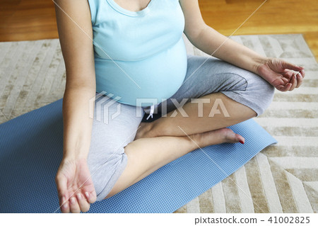 Pregnant woman meditating in lotus position Pregnant woman meditating in lotus position 41002825