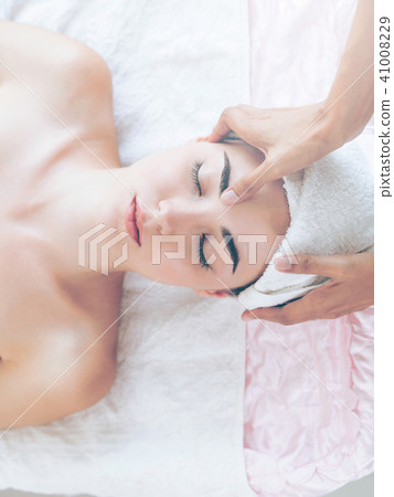 Woman gets facial and head massage in luxury spa. Woman gets facial and head massage in luxury spa. 41008229