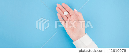 Female hand holding a white pill Female hand holding a white pill 41010076