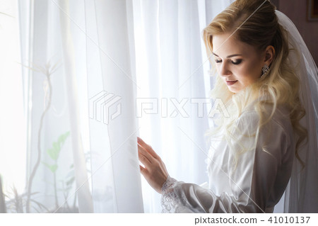 bride in a peignoir standing in front of the window bride in a peignoir standing in front of the window 41010137