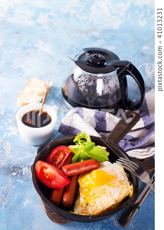 Homemade delicious breakfast on a pan with fried egg, toast, sausage, vegetable, black coffee 41013231