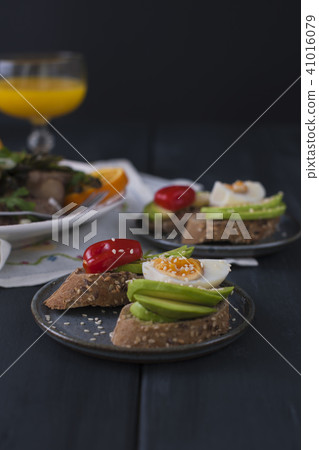 Toasts with avocado, yatsom and cherry tomatoes, on a black wooden background. Juice and delicious 41016079