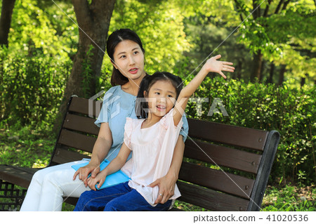 Mother and a girl sitting on a bench reading a book Mother and a girl sitting on a bench reading a book 41020536