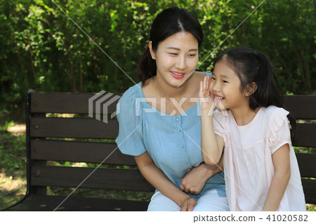 A girl whispering to her mom A girl whispering to her mom 41020582
