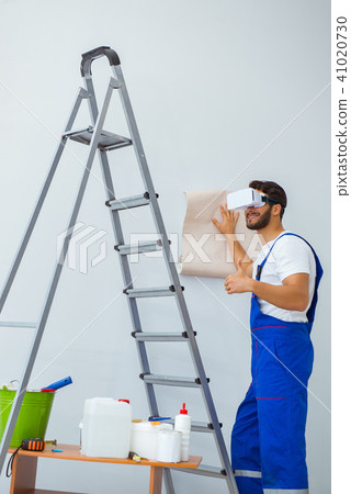 Man with VR glasses gluing wallpaper 41020730