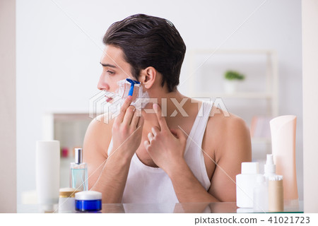 Young handsome man shaving early in the morning at home Young handsome man shaving early in the morning at home 41021723