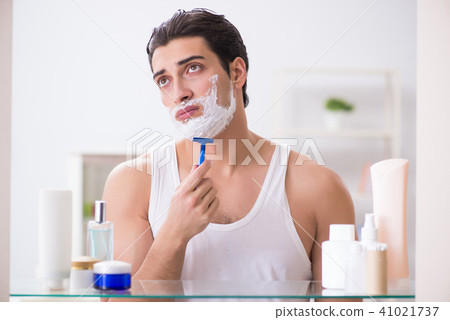 Young handsome man shaving early in the morning at home Young handsome man shaving early in the morning at home 41021737