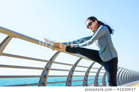 Girl warming up for a workout by the seaside Girl warming up for a workout by the seaside 41030637