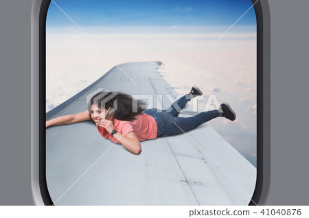 Woman with phone lies on plane wing in flight Woman with phone lies on plane wing in flight 41040876