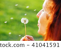 woman holding dandelion flowers on blurry green background. 41041591
