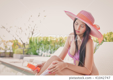 Swimsuit Concept. Beautiful girl in swimsuit is applying sunscre 41042747