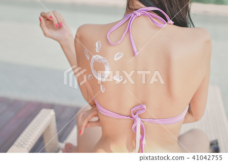 Swimsuit Concept. Beautiful girl in swimsuit is applying sunscre 41042755
