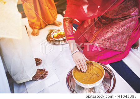 Women pasting turmeric (haldi) oil on bride's feet Women pasting turmeric (haldi) oil on bride's feet 41043385