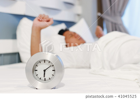 Alarm clock waking up at morning with a man sleepi 41045525