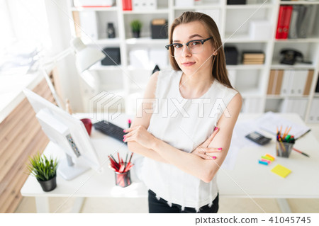 Beautiful young girl in an office is standing near a table. Beautiful young girl in an office is standing near a table. 41045745