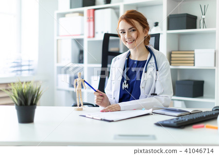 A beautiful young girl in a white robe is sitting at a table in the office. A beautiful young girl in a white robe is sitting at a table in the office. 41046714