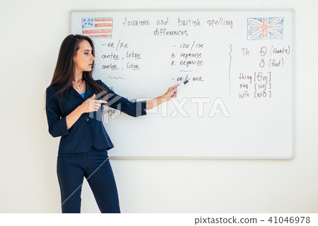 Teacher explaining differences between American and British spelling writing on whiteboard English Teacher explaining differences between American and British spelling writing on whiteboard English 41046978