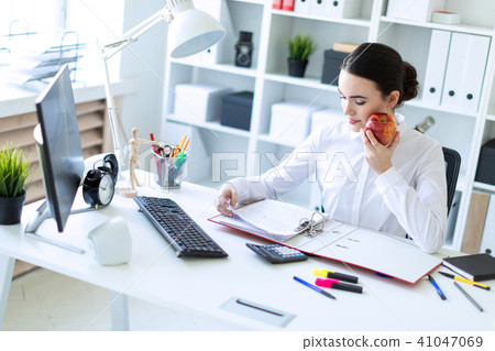 Young girl in the office working with documents and holding an apple. 41047069
