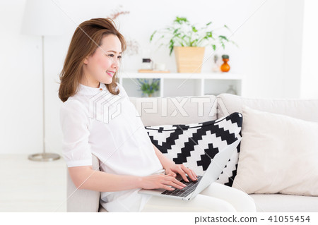 觀看一台便攜式計算機的婦女在屋子裡 觀看一台便攜式計算機的婦女在屋子裡 41055454