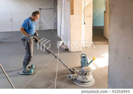 Laborer polishing sand and cement screed floor. Laborer polishing sand and cement screed floor. 41058945