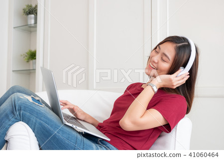 Asian woman listening music on headphone Asian woman listening music on headphone 41060464
