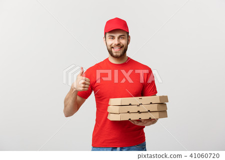 Pizza delivery concept. Young handsome delivery man showing pizza box and holding thumb up sign Pizza delivery concept. Young handsome delivery man showing pizza box and holding thumb up sign 41060720