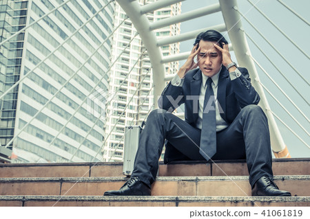 Young depressed businessman sitting on the stairs Young depressed businessman sitting on the stairs 41061819