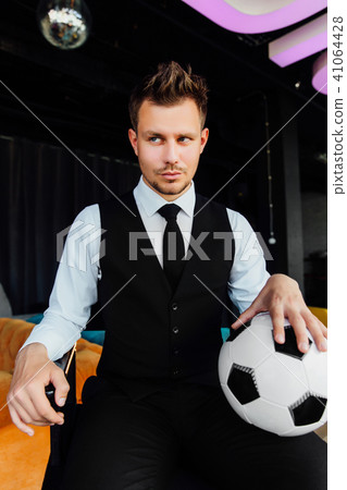 Stylish athletic man in a business suit and a soccer ball. Against the background of a loft wall. 41064428