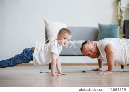 Image of happy dad and son pushing on floor Image of happy dad and son pushing on floor 41065559