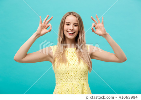 Happy young woman showing ok sign with fingers with big smile isolated on a blue background 41065984
