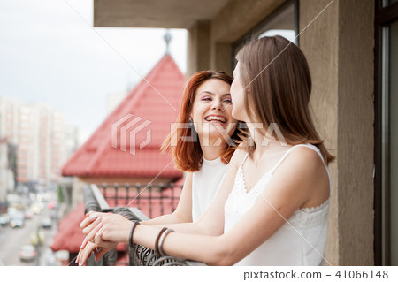 Two female friends talking and laughing at the balcony 41066148