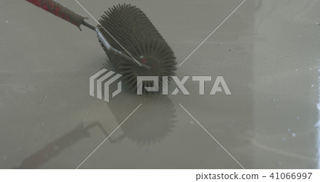closeup using spike roller to remove air bubbles from self leveling floor 41066997