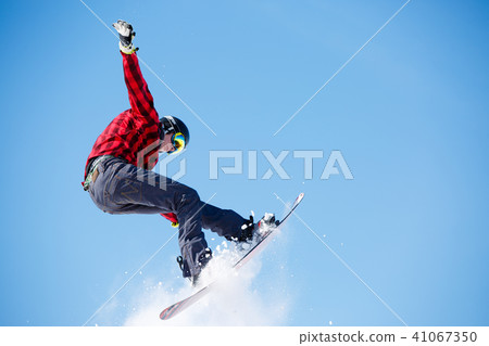 Photo of young sportive man jumping with snowboard Photo of young sportive man jumping with snowboard 41067350