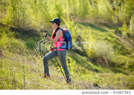 Photo of smiling sportswoman with walking sticks and backpack Photo of smiling sportswoman with walking sticks and backpack 41067363