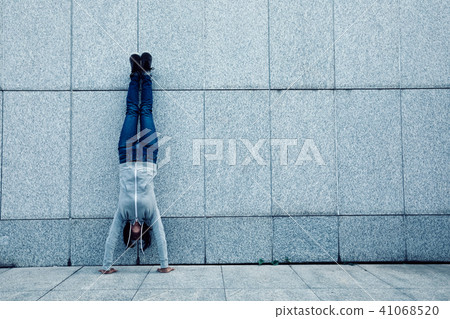 female hipster doing a handstand against wall female hipster doing a handstand against wall 41068520