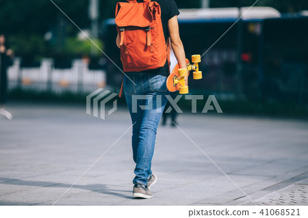 Woman walking with skateboard on city street Woman walking with skateboard on city street 41068521