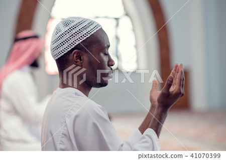 Two religious muslim man praying together inside the mosque Two religious muslim man praying together inside the mosque 41070399