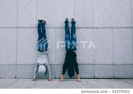 hipsters doing handstand against wall in city hipsters doing handstand against wall in city 41070402