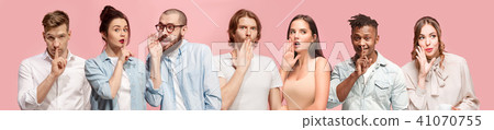 The young men and women whispering a secret behind hands over pink background The young men and women whispering a secret behind hands over pink background 41070755