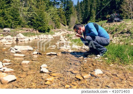 Young man drinking water from a spring. 41071403