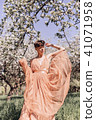 Girl in a pink dress is posing in a garden full  41071958