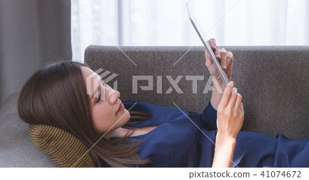 Woman is relaxing and reading tablet on sofa 41074672