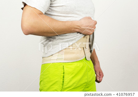 man showing back support belt under his T-shirt 41076957