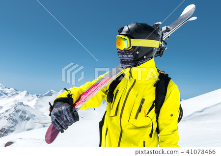 A large portrait of a skier in a protective helmet and glasses is a mask and scarf with skis on his 41078466
