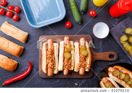 Picture on top of buns with sausages on cutting board, on table with cucumbers 41079219