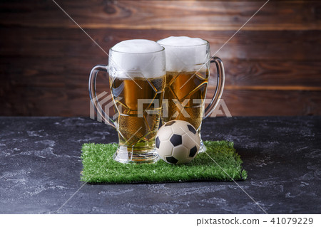 Photo of two beer mugs, green grass with soccer ball Photo of two beer mugs, green grass with soccer ball 41079229