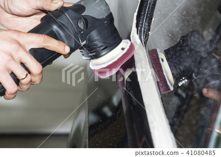 Car detailing - Hands with orbital polisher in auto repair shop. Selective focus. Car detailing - Hands with orbital polisher in auto repair shop. Selective focus. 41080485