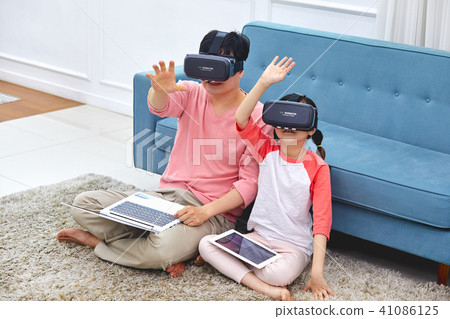 A scene in which a father and a daughter are happily resting in a VR game in a living room 41086125